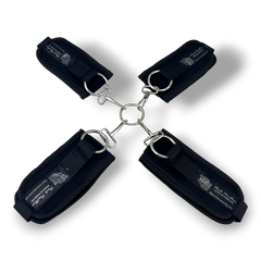 Glow&Vibe Bondage Lure negro, sistema de esposas de 4 puntos con velcro y conector central metálico para manos y pies.