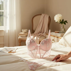 Conjunto de lencería Glow&Vibe Blush Temptation rosa con bustier de encaje floral y tanga a juego sobre una cama