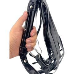 Glow & Vibe Gloss Whip látigo corto de charol brillante negro, material vinil, con tiras flexibles para juego íntimo.