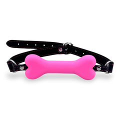 Glow&Vibe mordaza bucal rosa con forma de hueso de plástico suave y cinturón de cuero sintético negro.