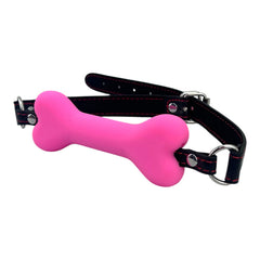 Glow&Vibe mordaza bucal rosa con forma de hueso de plástico suave y cinturón de cuero sintético negro.