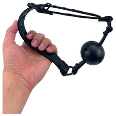 Mordaza bucal negra de cuero sintético con pelota rígida perforada de 4 cm de diámetro. Glow&Vibe.