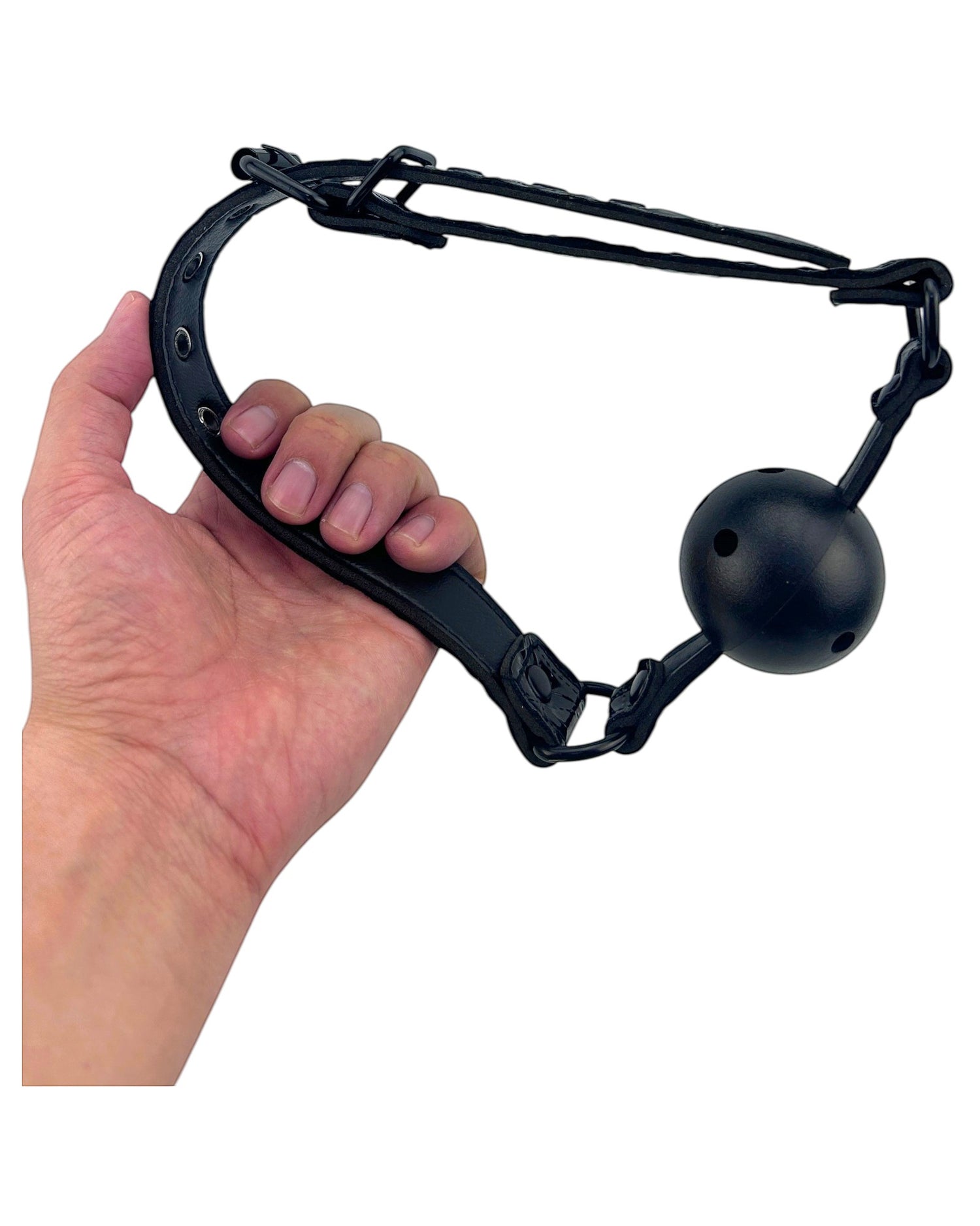 Mordaza bucal negra de cuero sintético con pelota rígida perforada de 4 cm de diámetro. Glow&Vibe.