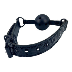 Mordaza bucal negra de Glow&Vibe con pelota rígida y cinturón de cuero sintético con detalles grabados.