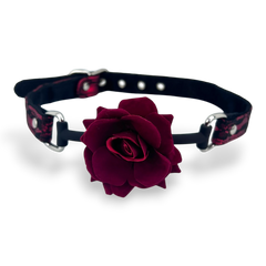Glow&Vibe Rose Gag mordaza de silicona rosa oscuro con correa ajustable de tela negra y detalles rojos.