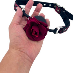 Glow&Vibe Rose Gag: mordaza bucal de silicona negra con rosa de terciopelo burdeos y correa ajustable de tela.